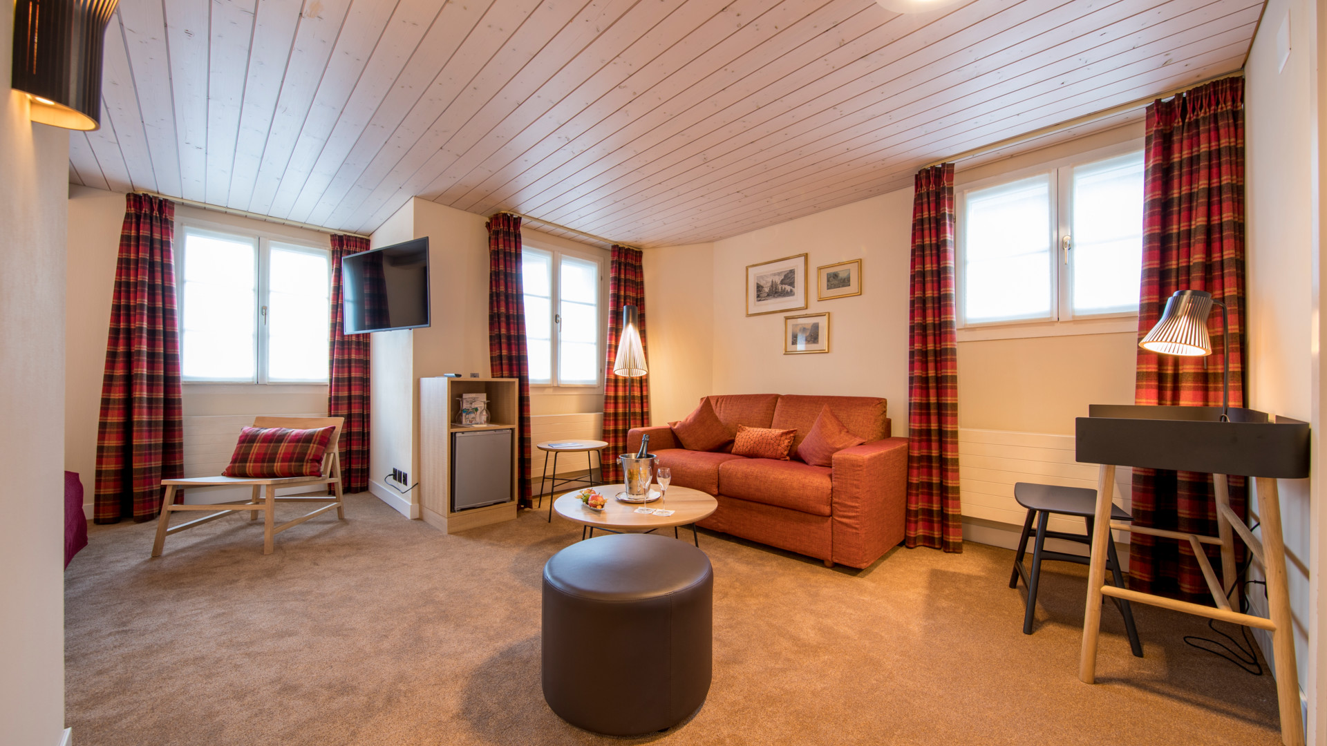 Cozy lounge with red tartan drapery and plush brown sofa, evoking a warm, inviting atmosphere for leisure or hospitality settings.