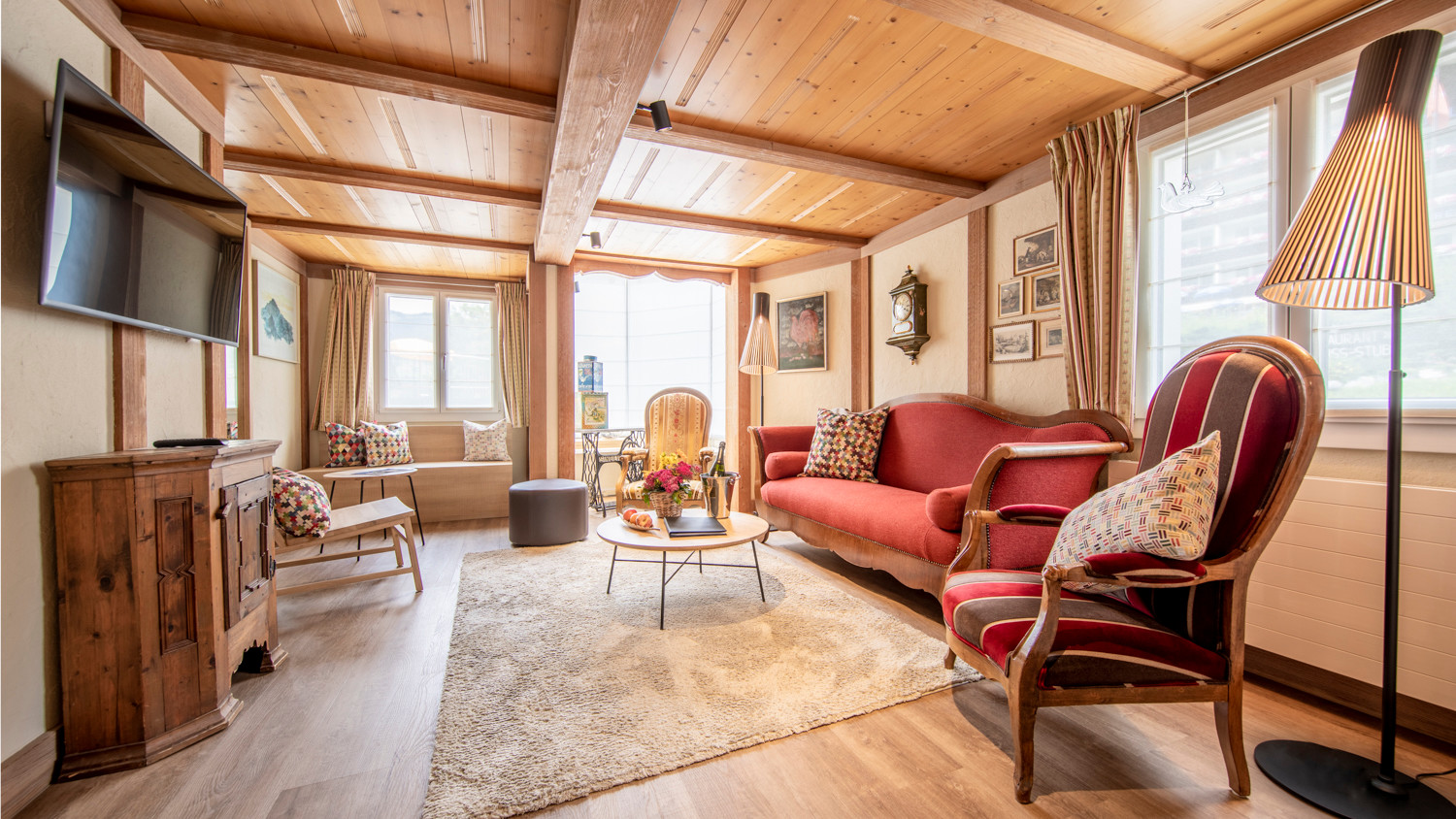 Cozy, wood-paneled living room with red upholstered furniture and warm lighting, perfect for a tranquil retreat in a rural home.