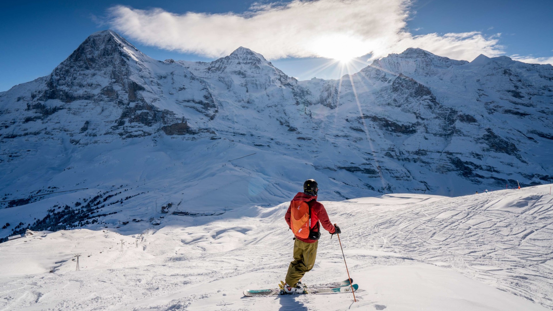 Skier in bright attire against pristine white snow and majestic mountain peaks, radiating a sense of adventure and winter sports thrill.