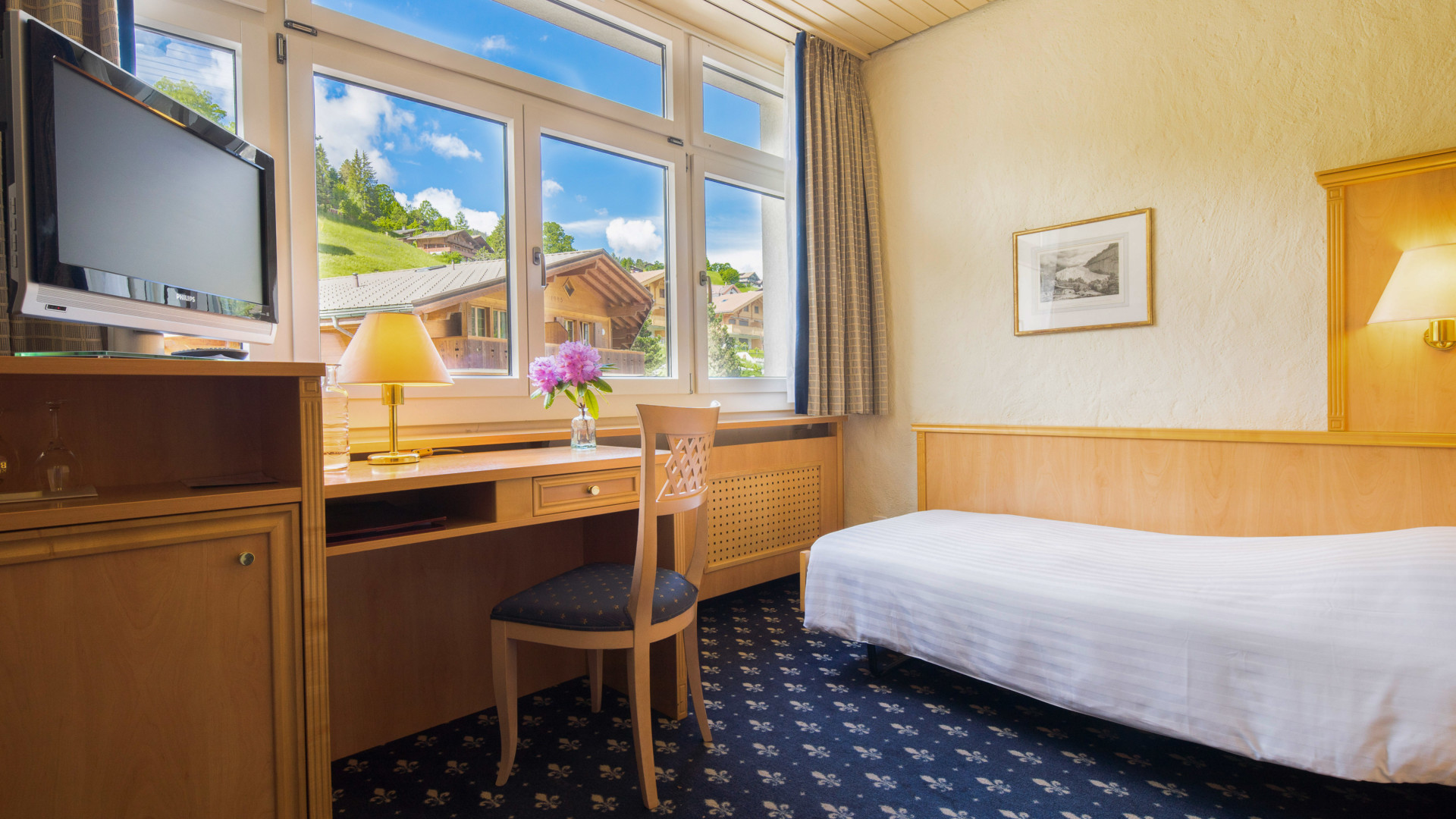 Bright, cozy hotel room with a scenic mountain view and warm wooden furnishings, inviting relaxation for travelers.