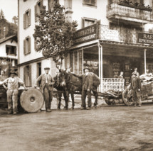 Sepia-toned historical street scene with horse-drawn carts and early 20th-century urban setting, evoking a nostalgic and bustling marketplace atmosphere.