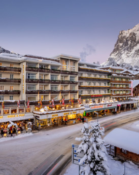 Snow-covered alpine resort with warmly lit storefronts, inviting travelers into a cozy winter escape, perfect for ski enthusiasts.