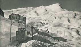 Vintage black-and-white photo of a snow-covered alpine landscape with a tram, exuding a serene, historical charm, ideal for travel and history enthusiasts.