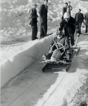 Vintage black-and-white photo of a bobsled team racing down an icy track, capturing the thrill and intensity of competitive winter sports.