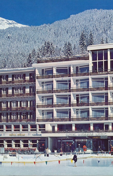 Winter resort hotel surrounded by snow-covered pines, exuding a cozy, inviting atmosphere for ski enthusiasts.
