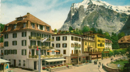 Quaint Alpine village with colorful buildings and snow-capped mountain backdrop, evoking a serene, picturesque setting ideal for tourism.