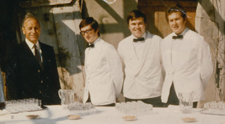 Vintage outdoor event with four men in white serving attire, an inviting, rustic setting ideal for hospitality industry showcases.