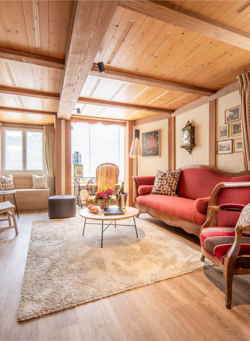 Cozy, wood-paneled living room with red sofas and vintage decor, radiating warmth and traditional charm for real estate enthusiasts.