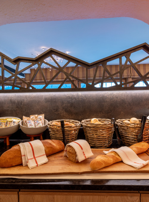 Warm, rustic bakery display with fresh bread in baskets, under arched window frames, creating an inviting, cozy ambiance for artisanal food lovers.