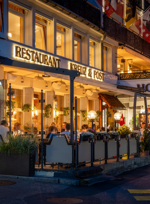 Twilight at a bustling street-side restaurant, highlighted by warm lighting and lively dining scenes, evokes a cozy, welcoming ambiance for tourists and food lovers.