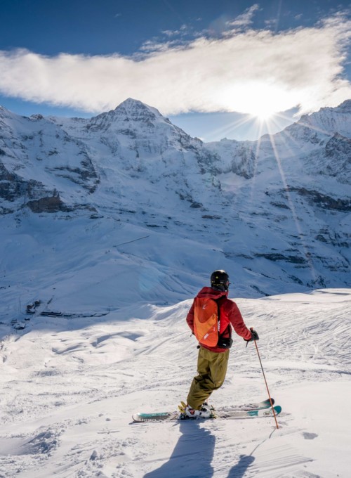 Skier in bright attire against pristine white snow and majestic mountain peaks, radiating a sense of adventure and winter sports thrill.