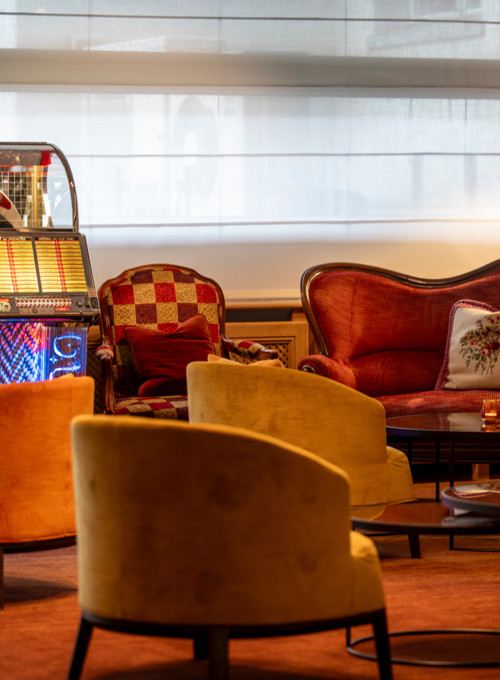Warm-toned living area with richly colored vintage sofas and a vibrant jukebox, creating a nostalgic and cozy ambiance for leisure or hospitality settings.