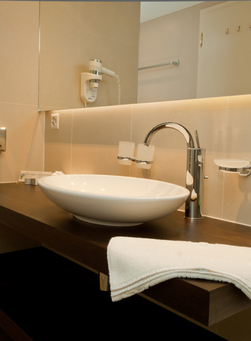 Contemporary neutural-toned bathroom with a sleek white basin and modern amenities, offering a clean and tranquil setting.