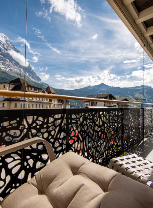 Alpine-view balcony adorned with modern outdoor furniture, set against a dramatic mountain backdrop, capturing serene luxury for travel and leisure.