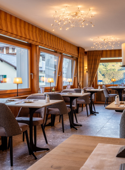 Cozy restaurant interior with warm lighting and mountain views, evoking an inviting, relaxed atmosphere for dining.