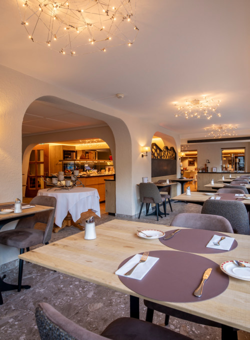 Warmly lit, upscale restaurant interior with arched doorways and elegant chandeliers, presenting a cozy and sophisticated dining atmosphere.