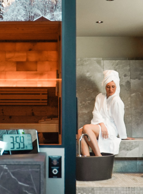 Soothing spa setting with wooden sauna and modern bathtub, featuring a serene woman in a white robe and towel, ideal for wellness retreats.
