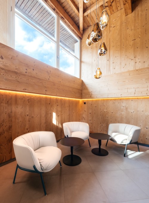Bright, wood-paneled room with contemporary white chairs and unique golden lights, exuding a warm, inviting ambiance for interior design showcases.