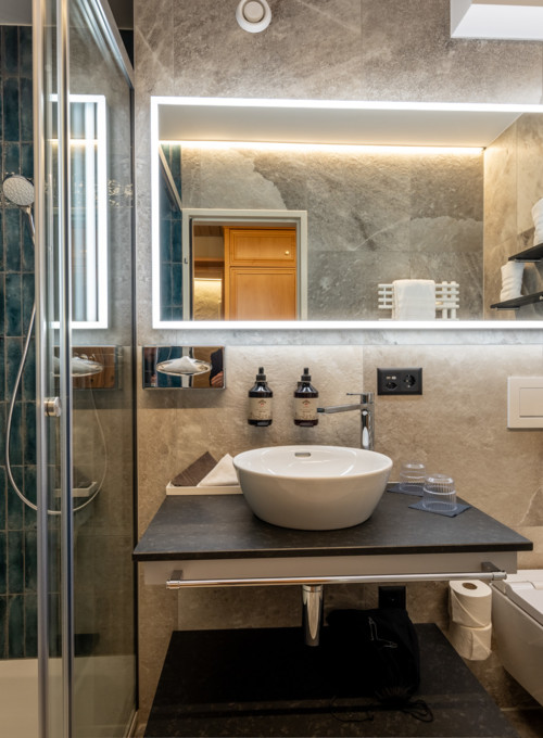 Elegant bathroom with deep blue tiles and sleek grey walls, presenting a serene and upscale atmosphere for design aficionados.