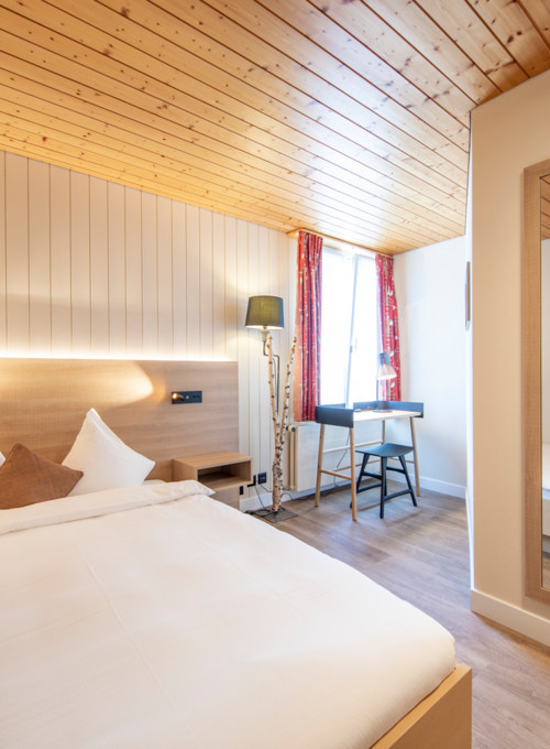 Cozy hotel room featuring warm wooden accents and crisp white bedding, evoking a serene, welcoming atmosphere for travelers.