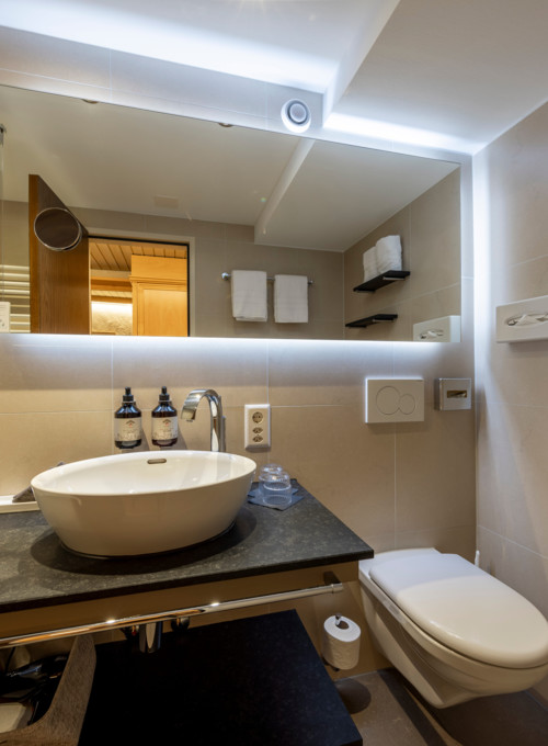 Streamlined hotel bathroom with beige tiles and sleek fixtures, exuding a clean and serene ambiance for travelers.