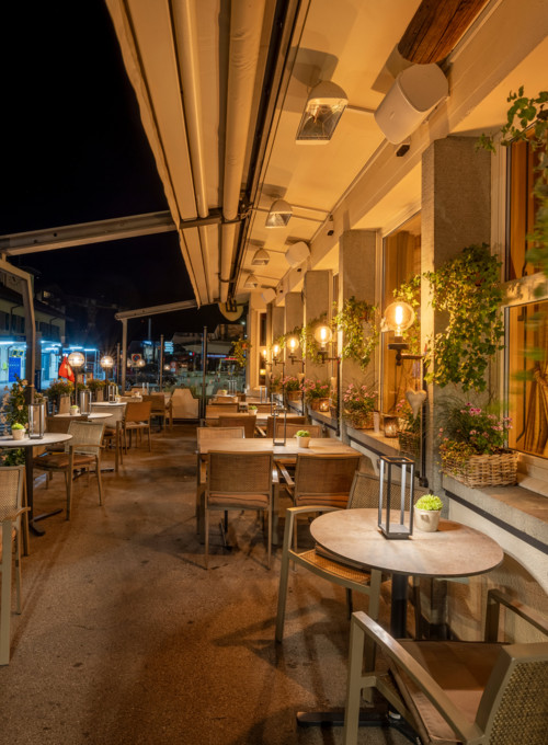 Cozy outdoor restaurant patio at twilight with warm lighting and elegant wooden furniture, capturing a welcoming and serene dining atmosphere.