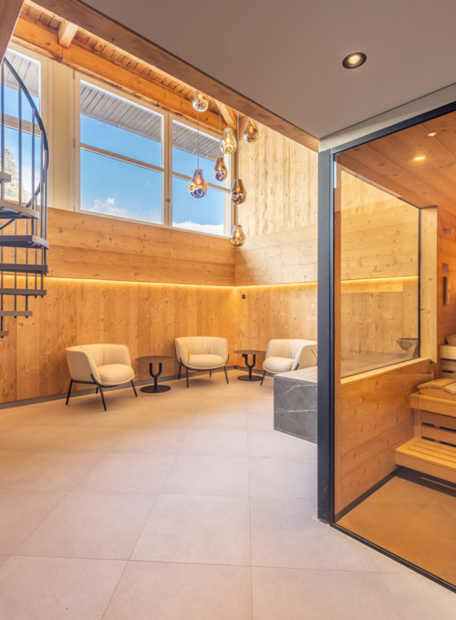 Warmly lit sauna room with natural wood panels and modern spiral staircase, exuding relaxation and elegance for wellness spaces.