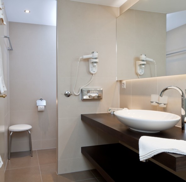 Neutral-toned bathroom with sleek fixtures and ample light, exuding a serene and modern appeal for the hospitality industry.