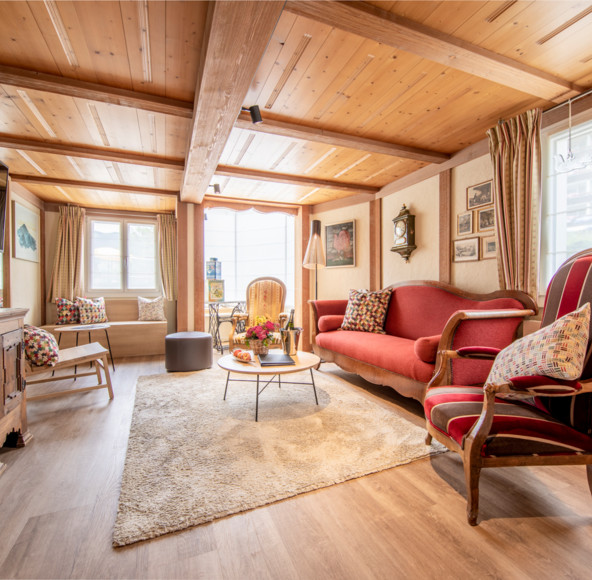 Cozy, wood-paneled living room with red upholstered furniture and warm lighting, perfect for a tranquil retreat in a rural home.