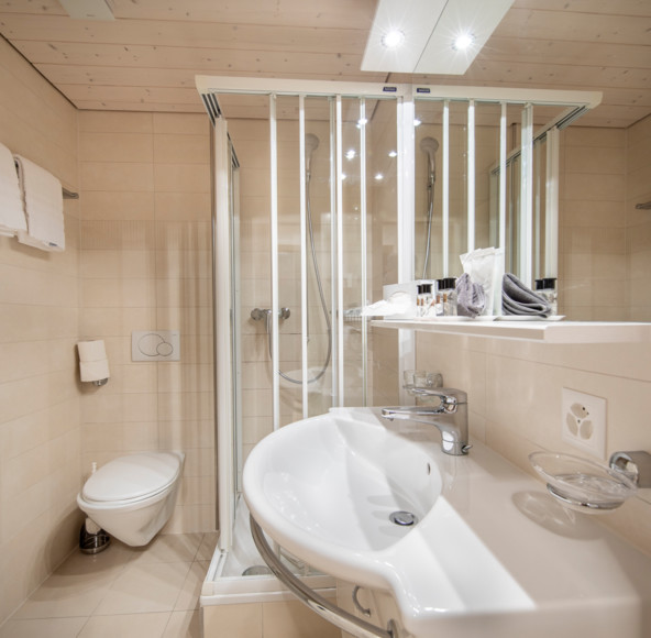 Beige-toned bathroom with sleek, modern fixtures and a clear glass shower, emphasizing cleanliness and simplicity for real estate showcases.