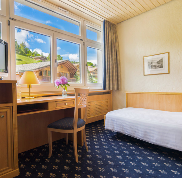 Bright, cozy hotel room with a scenic mountain view and warm wooden furnishings, inviting relaxation for travelers.