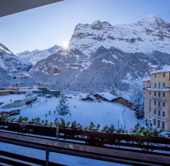 Winter sunrise over a snow-covered mountain village, viewed from a balcony, evoking a serene and picturesque getaway for travelers.