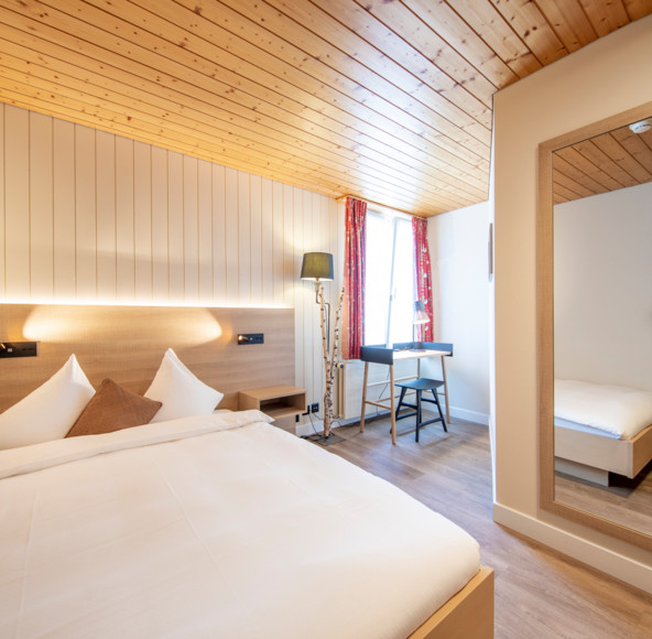 Cozy hotel room featuring warm wooden accents and crisp white bedding, evoking a serene, welcoming atmosphere for travelers.