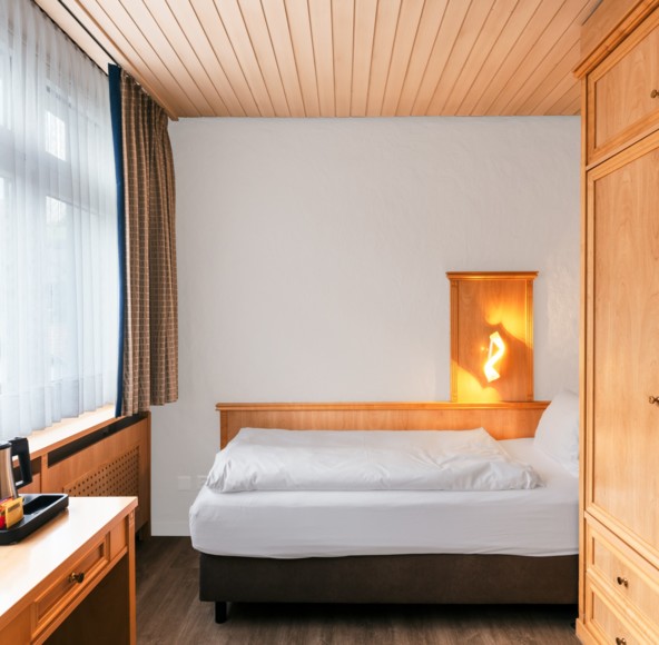 Cozy hotel room with warm wooden furniture and soft natural lighting, creating a peaceful retreat for travelers.