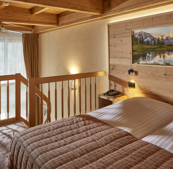 Cozy wooden cabin bedroom with plaid bedding and serene mountain artwork, evoking a tranquil, rustic retreat vibe ideal for relaxation.