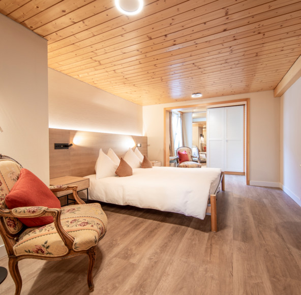 Cozy hotel room with warm wooden ceilings and elegant furnishings, inviting a sense of relaxation and comfort for travelers.