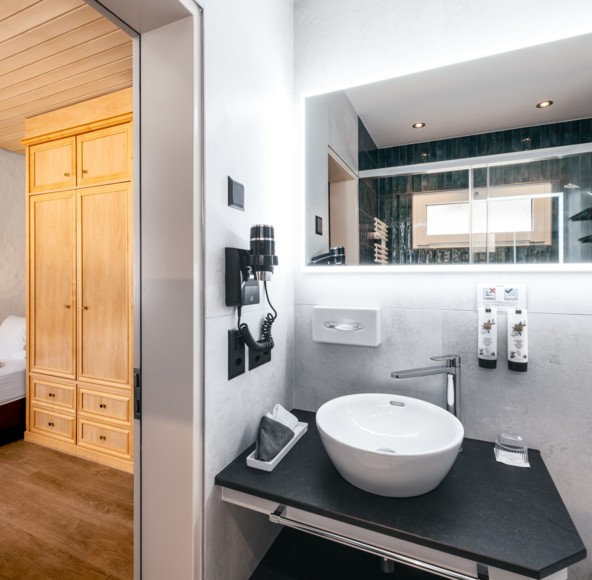Sleek hotel room seamlessly integrates sleep and wash areas, with warm wooden tones offering a homely, inviting atmosphere.