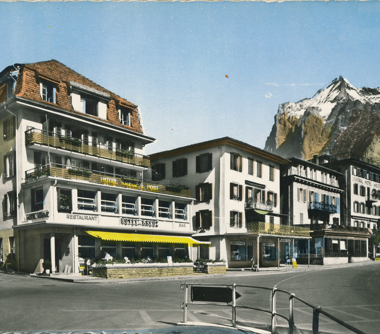 Quaint Alpine village hotels with sunny facades and majestic mountain backdrop; serene and inviting for travel and tourism sectors.