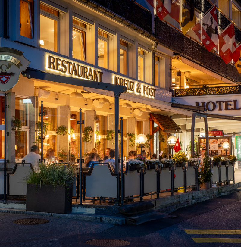 Twilight at a bustling street-side restaurant, highlighted by warm lighting and lively dining scenes, evokes a cozy, welcoming ambiance for tourists and food lovers.