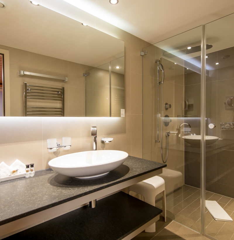 Sleek bathroom with neutral beige tiles and modern fixtures, creating a clean and serene ambiance for hospitality settings.