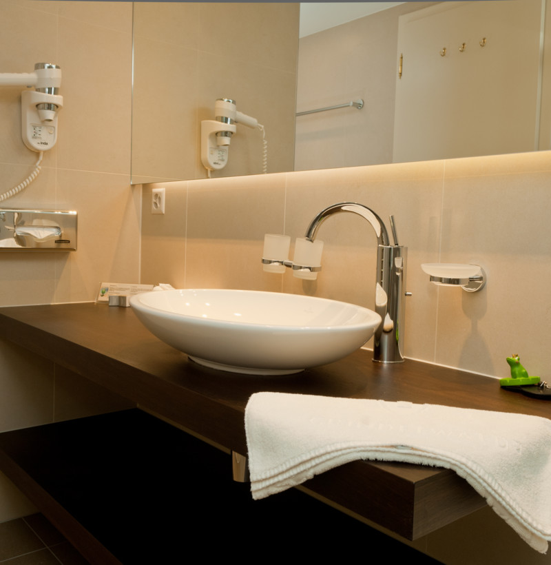Contemporary neutural-toned bathroom with a sleek white basin and modern amenities, offering a clean and tranquil setting.