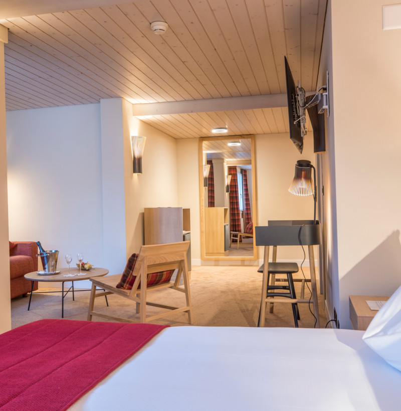 Cozy hotel room blending warm red accents with modern furniture, fostering a welcoming ambiance for travelers.