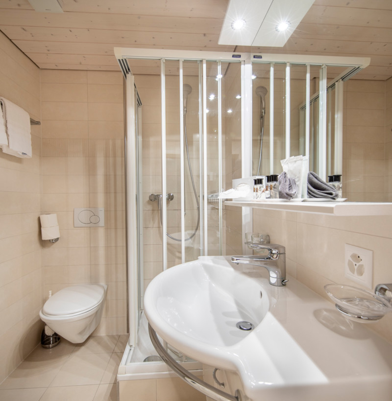 Beige-toned bathroom with sleek, modern fixtures and a clear glass shower, emphasizing cleanliness and simplicity for real estate showcases.
