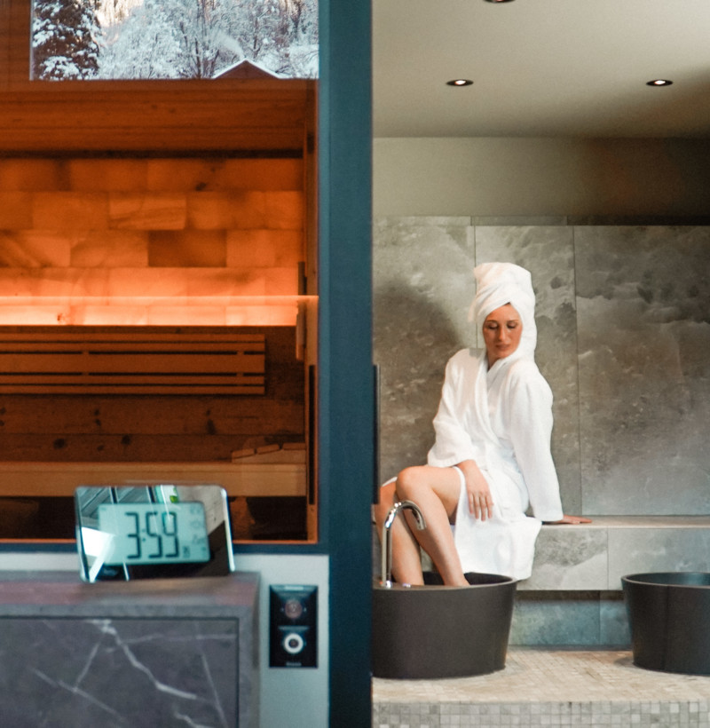 Tranquil spa setting with a woman in white robe reflecting peacefulness, ideal for wellness industry promotions.