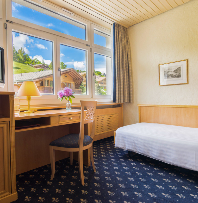 Bright, cozy hotel room with a scenic mountain view and warm wooden furnishings, inviting relaxation for travelers.