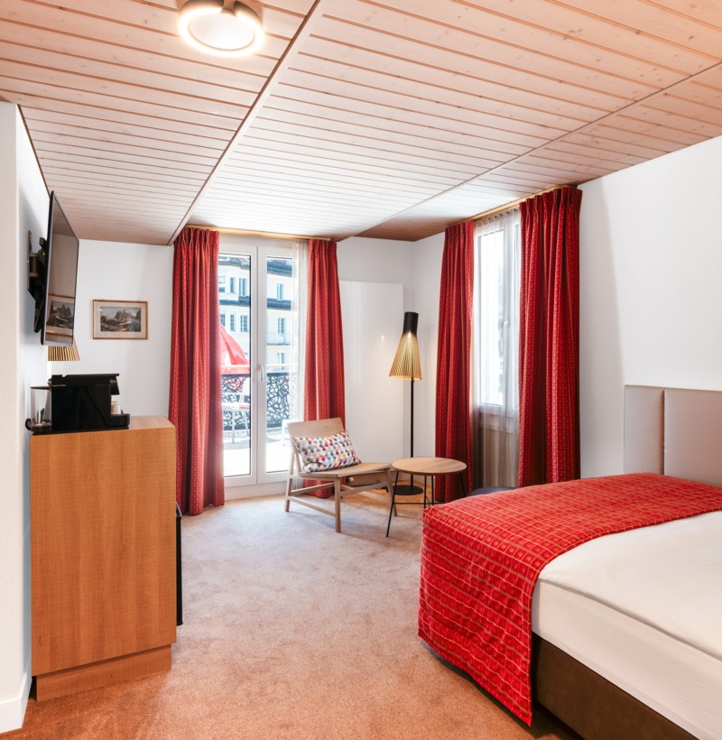 Cozy hotel room with red accents and wooden ceilings, creating a warm, inviting atmosphere for travelers.