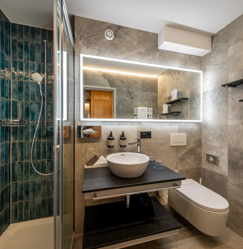 Stylish bathroom with blue tiled shower and sleek marble walls, projecting a serene, modern feel perfect for design-forward homes.