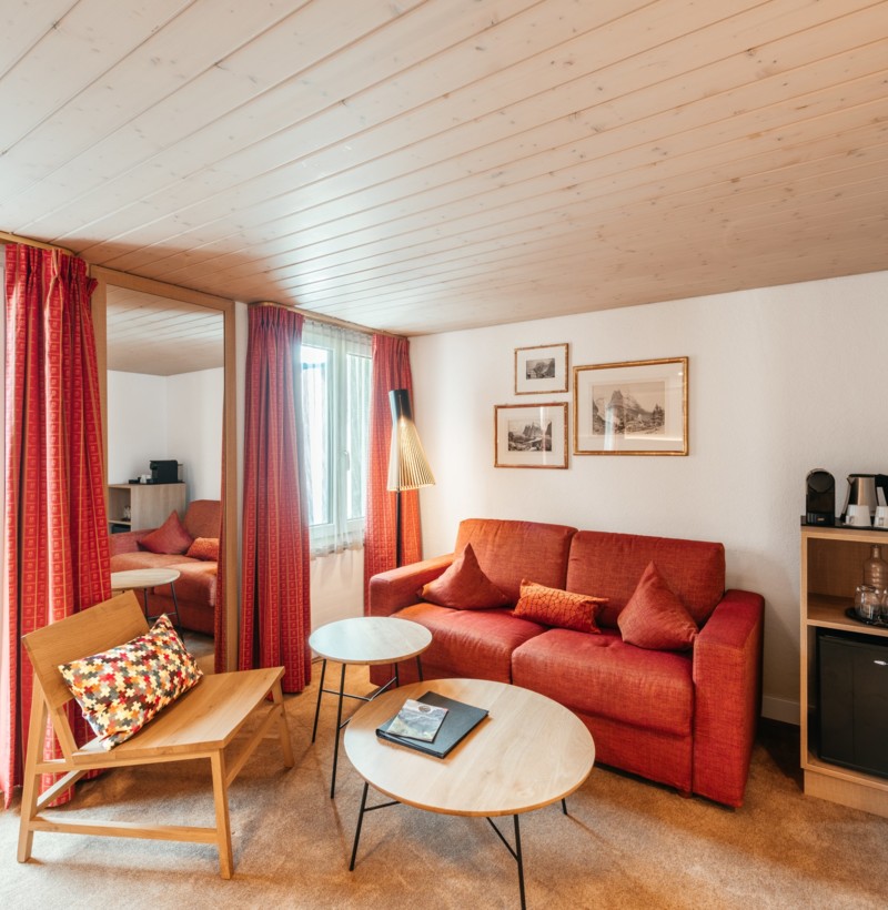 Cozy and warm living space with vibrant red sofas and wooden accents, ideal for relaxation and hospitality in a home setting.