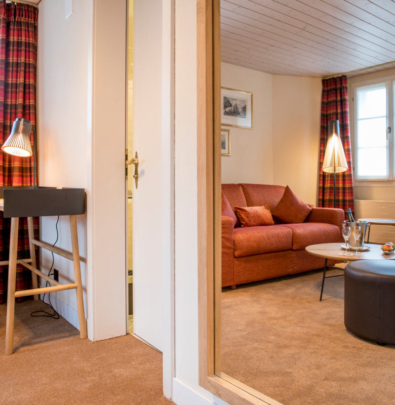 Cozy interior with a red plaid couch, warm lighting, and wooden accents, offering a homely and inviting atmosphere for relaxation.