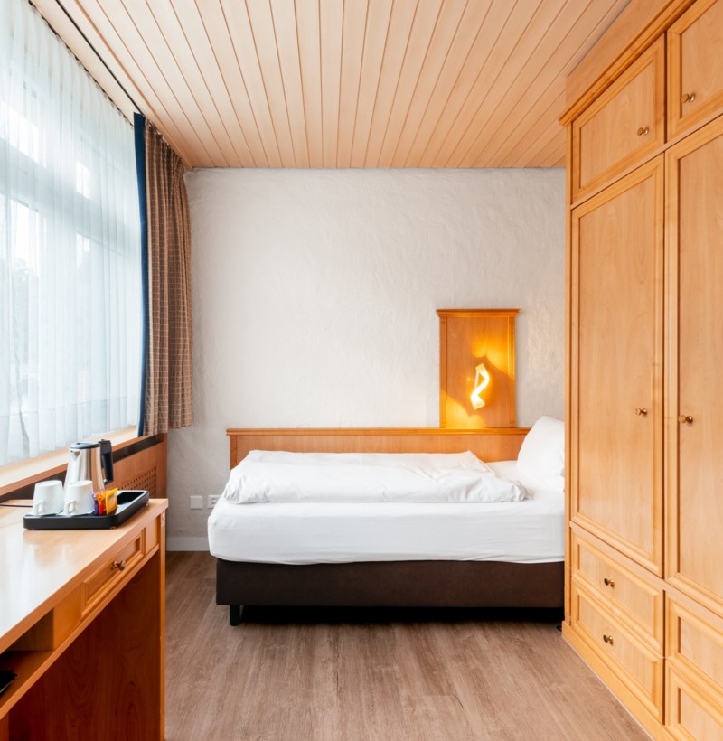 Cozy bedroom with warm wood accents and soft natural light, creating a serene ambiance ideal for rest and relaxation.